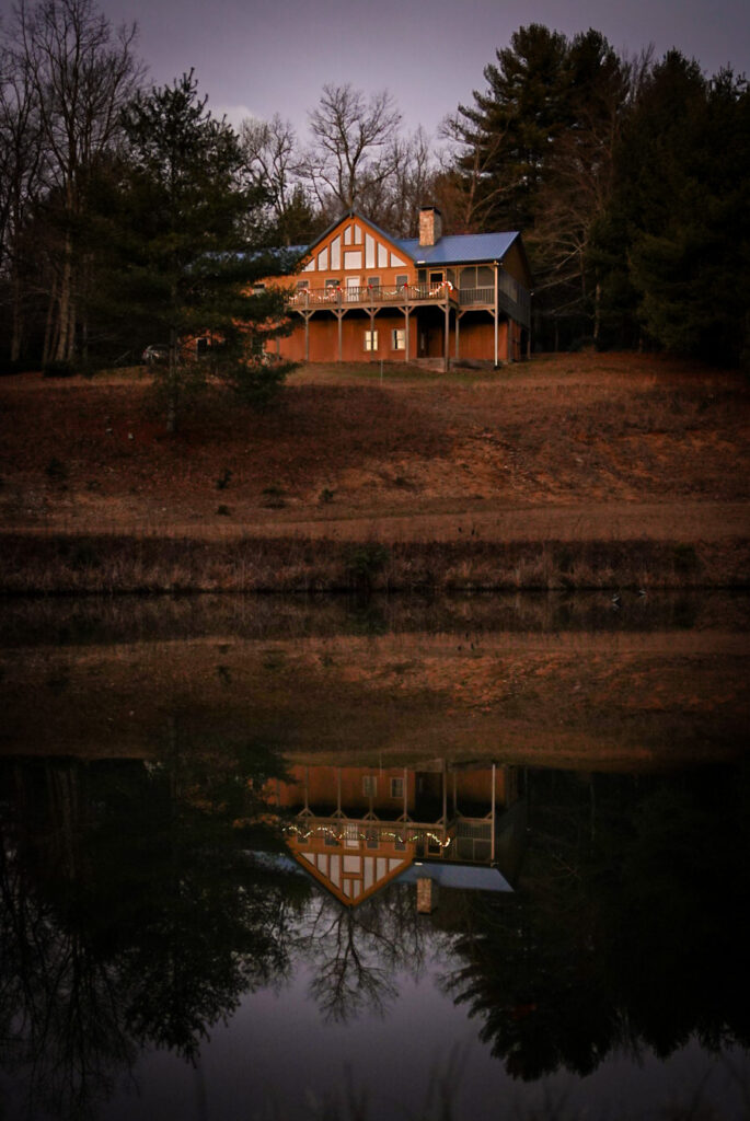 Cabin with blue roof and it's reflection in a pond